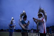 Lawrence High sousaphone players DaVaughn Pellis, junior, left, Max Bailey, senior, and Reid Hildenbrand, junior, warm up before practice Tuesday at the football stadium.