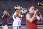 Lawrence High School junior mellophone player Richard Koontz stays in step with the marching band as he sports a straw hat during practice Tuesday at the football stadium.