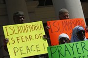 Demonstrators hold up signs during a news conference Wednesday on the steps of New York’s City Hall. More than 50 leaders of Muslim organizations in New York City are defending plans by developers to build an Islamic community center near ground zero.
