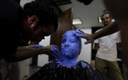 Mexican makeup artist Cristian Jauregui, left, works on the mold of the zombie mask of Claudia Calvino, Cuban co-producer of the film “Juan de los Muertos” or “Juan of the Dead” Thursday in Havana.