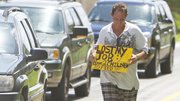 A man — he did not wish to be identified — who lost his job two months ago after being hurt on the job collects money for his family on a Miami street corner Thursday. He said he collects unemployment but added it does not cover the cost of living.