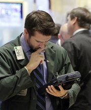 Trader Luke Dalton works on his hand-held device Thursday on the floor of the New York Stock Exchange. Despite the economic doldrums, the stock market put together an 11 percent upswing over the past three months.