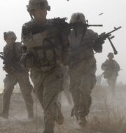 A U.S. soldier returns fire as others run for cover during a firefight with insurgents in the Badula Qulp area, west of Lashkar Gah in Helmand province, southern Afghanistan, near Marjah, in this Feb. 14, 2010, file photo. U.S. Marines were conducting an offensive against the Taliban.