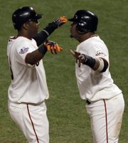 San Francisco’s Edgar Renteria, left, and Juan Uribe celebrate after scoring during the Giants’ seven-run eighth inning of Game 2 of the World Series. The Giants won, 9-0, for a 2-0 lead in the series Thursday in San Francisco.