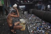 Prakesh, a migrant worker takes a bath Oct. 23 near an open sewer at a slum in Mumbai, India. When U.S. President Barack Obama visits India Saturday he will find a country of startlingly uneven development and perplexing disparities, where more people have cell phones than access to a toilet, according to the United Nations.