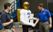 Astronaut Michael Barratt greets Robonaut 2 at NASA’s Johnson Space Center in Houston. Robonaut 2 is made of aluminum and nickel-plated carbon fiber.
