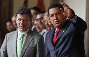 Venezuela’s President Hugo Chavez, right, waves to journalists Tuesday as Colombia’s President Juan Manuel Santos looks on after a welcoming ceremony at Miraflores presidential palace in Caracas, Venezuela.
