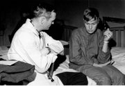 Weighing 55 pounds less than he did at the start of his captivity 11 months earlier, Steve Woelk talks with an American doctor after he and 81 surviving crewmen were released from North Korean captivity in December 1968.