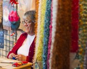 M.J. Nuss, Lawrence, knits a scarf while talking with shoppers at the Bizarre Bazaar art show held Saturday at the Lawrence Arst Center. The event featured plenty of arts and crafts for sale and live music.
