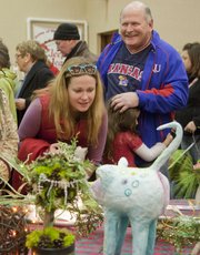 Vera Long, left, Lawrence, looks over a vendor's holiday gift items, as her daughter Olive, then 5, hugs her grandfather, Tom Ackerly, Lawrence, in this 2010 photo taken at the Holiday Farmers Market.