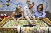 Jaclyn Long, 16, left, stands with BJ and Alecia Gray as they play with their 7-month-old son, Benjamin, in the newly renovated nursery at West Side Presbyterian Church on Sunday. Long, a junior at Free State and a Girl Scout Ambassador 7744, completely redesigned the church’s nursery as a project to receive her Gold Award.