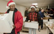 J.R. Demby, left, and his daughter Rianon Wallace-Demby pick up 18 Christmas meals to deliver to North Lawrence residents. The two were picking the meals up during the Lawrence Community Christmas dinner at First United Methodist Church.