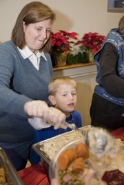 Harriett Bannister, Lawrence, assists her son Evan, 6, in serving up mashed potatoes at the Lawrence Community Christmas dinner at First United Methodist Church. The two were among hundreds of volunteers for the annual dinner.