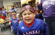Kennedy School student Mikey Gregorio belts out the lyrics to "I&squot;m a Jayhawk" as he and other students in Jill Anderson&squot;s class make their rounds performing Kansas University and Kansas State University songs and chants for other classes Friday, Jan. 28, 2011.
