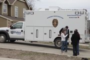 Residents in the area of the 700 block of Michigan Street visit as Lawrence police investigate the scene where a dead body was discovered Sunday afternoon in a creek bed and wooded area just east of Hawk's Pointe Apartments I and some nearby townhouses. In the background is a police investigation support van.