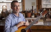 Guitar maker Leo Posch is pictured in his shop with one of his guitars Wednesday, March 9, 2011. Posch, who plays banjo in the local band Midday Ramblers, said that he couldn't imagine being an instrument maker without also being a musician.
