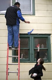 Libby Johnson of Lawrence tosses a spray bottle of glass cleaner to Michael Wade Smith as the two work to wash the windows of Kendall Simmons' Lawrence home Thursday, March 31, 2011. These two Kansas University seniors, along with many other KU students, spent the morning and afternoon doing odd jobs as part of The Big Event, a volunteer opportunity organized by KU Student Senate.