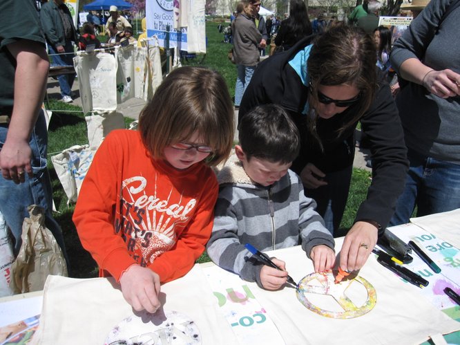 From left, Ella Diederich, 8, and her brother Owen, 5, decorate reusable bags with some help from their mom, Becca Diederich. They were at The Merc's booth at the Earth Day Celebration on Saturday, April 16, 2011, at South Park.