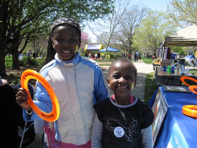 Thayu Kimori, 8, and her sister Wendo, 6, both of Lawrence, picked up Frisbees at the WellCommons booth during the Earth Day Celebration in South Park.