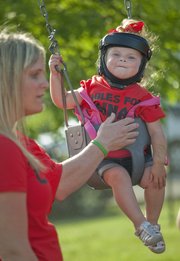 Courtlynn “Coco” Shutt, 2, swings next to her mother, Ali Shutt, of Eudora, Thursday outside the Eudora Community Center where area officials were meeting with Kansas Department of Transportation officials to discuss Kansas Highway 10 safety issues between Kansas City and Lawrence. Courtlynn suffered a broken vertebra in a crossover crash on K-10 near Eudora on April 16 that killed her brother, Cainan Shutt, 5. Family and friends held a candlelight memorial for Cainan during the KDOT meeting. See a video of the memorial service at LJWorld.com.