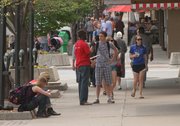 A Save the Children worker, center in red, speaks with a man on Massachusetts Street on June 1. Save the Children workers have been spotted downtown for the last couple of months soliciting donations for their organization.