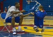 Kansas forward Thomas Robinson, left, helps 6-year-old Danny Phalen, of Lawrence, into some KU warmup gear during Bill Self’s parent-child basketball camp Friday, June 3, at Allen Fieldhouse.