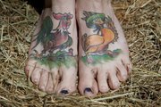 Jenn Cole-Hiatt’s tattoos include a rooster flirting with a duck on her feet. The tattoos were based on illustrations from an old postcard.
