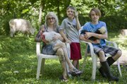 From left Jenn Cole-Hiatt, owner of Revolution Mama Ranch, holds Big John, a Coronation Sussex rooster, while her son Phoenix holds a young Indian Runner duck and her son Zane sits with a white-crested chocolate pullet.