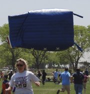 In this June 4, 2011, photo, participants in an Oceanside, N.Y., soccer tournament run from an airborne inflatable "bounce house" after high winds sent it flying, injuring 13 people, one critically. Saturday&squot;s inflatable mishap is the latest in a growing series of similar accidents, experts say.