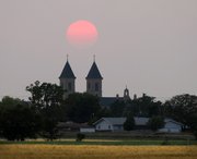 The sun is almost opacified by smoke that drifted over Kansas from wildfires in Arizona as it sets behind the Cathedral of the Plains Tuesday, June 7, 2011, in Victoria.