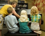 From left, Drew Bond, 11; Olivia Bond, 9; and Taylor Morstorf, 10, watch as piano instructor Karla Grether demonstrates which notes to play during a piano lesson June 23 at her home. Grether uses a teaching method called Simply Music.