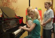 Olivia Bond, 9, practices a song at the piano as Taylor Morstorf, 10 and Drew Bond, 11, sing along June 23 at piano instructor Karla Grether’s home.
