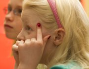 Piano student Olivia Bond, 9, points to her head as instructor Karla Grether tells her students what they need to remember for the next lesson.