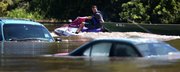 Tim Hogan pulls a jon boat behind his jet ski as he floats past cars owned by Terrible's Casino employees who couldn't move them before flood waters surrounded them Tuesday morning, June 28, 2011, in St. Joseph, Mo. Hogan was going to his rental home on the banks of the river to retrieve what he could from the flooded property.