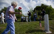 History expert Iona Spencer brings a small bouquet of flowers to the grave of Christopher Columbus Blake, a Union soldier in the Civil War, during a ceremony to commemorate the marking of the grave at Stull Cemetery with a gathering of descendants Saturday. The ceremony was performed by members of the Lawrence chapter of the Sons of Union Veterans of the Civil War. Spencer, who helped locate the whereabouts of the grave, explained that she used a combination of cemetery records that indicated plots and an old technique called "water witching" to find it.