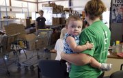 11-month-old Savannah Bennett, hangs on to her mother, Carrie Bennett, as she waits in line for an application at Just Food Tuesday, July 19, 2011.