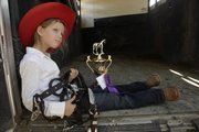 Halley Flory, 6, rests in the back of a horse trailer to admire the grand champion trophy she won in her age group at the horse show at the Douglas County Fair Sunday, July 31, 2011.