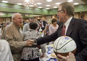 After being presented a signed 2010-2011 KU men's basketball, David Booth, chairman and CEO of Dimensional Fund Advisors, shakes hands with Jack Arensberg. Booth's first job was working for Jack at Arensbergs shoes. Booth, a 1964 LHS graduate and owner of the original rules of basketball, was the keynote speaker at the event.