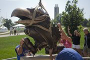 A new bronze Jayhawk sculpture landed outside the east side of the Anderson Family Football Complex on Thursday, Sept. 1, 2011. The sculpture will begin a tradition for the football players to touch the Hawk's beak for luck when exiting the locker-room during games. Setting the sculpture in place from left is Eric Epperson, with Fullbright Sign, Lawrence, John Free, of The Bronze Horse, Pawhuska, Okla., the sculptor, and his wife Cindy Free.