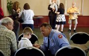 Firefighter Todd Dwyer gives his son, Parker, 4, a Lawrence Douglas County Fire Medical coin following a news conference on Friday, Sept. 9, 2011 in which those to be honored with the Lawrence Chamber of Commerce Valor Award were announced. Dwyer, who was a responder in a 2010 house fire on Harper Street was among those presented with a Lifesaving Award.