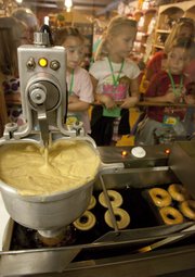 Doughnut rings drop into hot oil to fry at Louisburg Cider Mill. Visitors, like these kindergartners from Morse Elementary School in Overland Park, can watch the small production line through a window.