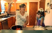 Aniela Kiekel slowly drips some melted marshmallows together to make popcorn balls with her daughter, Shasta, 3. Kiekel says Shasta enjoys helping to make chocolate cake.