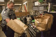 Officer Michael Ramsey processes items that were found in a stolen car. He had to use a roller storage cabinet for a work surface in the garage under the Judicial and Law Enforcement Center.
