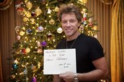 This Monday, Dec. 19, 2011 image release by David Bergman / PSG shows musician Jon Bon Jovi holding a sign from his home in Red Bank, N.J. Bon Jovi wants duped fans to know he&squot;s not dead, and he has posted a photo proving it. False reports of the musician&squot;s death spread online after a fake news release surfaced on social media sites. Bon Jovi is shown in this picture holding a sign that reads, "Heaven looks a lot like New Jersey." Below that is scrawled Monday&squot;s date.