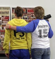 From left, Amanda Verynck of Lawrence, 23, former girlfriend of Preston Scheibler, gets a hug from Mistie Copas-Thomas, Preston’s mother, as they look over a collage during a benefit basketball tournament Saturday.