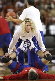 Andrea Hudy, associate director of strength and conditioning for the men's and women's basketball teams, stretches center Jeff Withey before tipoff against Texas on Saturday, Jan. 21 at the Frank Erwin Center in Austin. Hudy's responsibilities reach far beyond stretching and include tailoring workout regimens for individual players and monitoring calorie intake