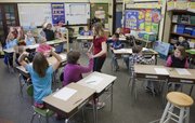 Woodlawn School teacher Rachel Gilmore goes around her classroom to join her fourth-graders in a morning high-five greeting. Her class of 14 students is the smallest in the Lawrence school district.