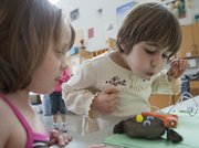 Helen Henry, right, blows on her flying squid to dry the glue-attached eyeballs as she and Molly Kelly participate in a spring break guerrilla art workshop Tuesday at the Lawrence Arts Center.
