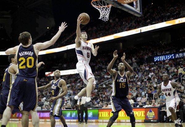 Atlanta Hawks' Kirk Hinrich (6) puts up a basket between Utah Jazz' Gordon Hayward (20) and Derrick Favors during triple overtime of an NBA basketball game, Sunday, March 25, 2012, in Atlanta. Atlanta won 139-133 in the NBA's first quadruple-overtime game since 1997.
