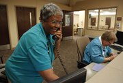 Lawrence Memorial Hospital volunteer Joanne Hurst takes a phone call from the registration desk next to fellow volunteer Corinne Geddings on Friday, April 6. Hurst has been volunteering with LMH for nine years and prior to that served on the board of trustees.